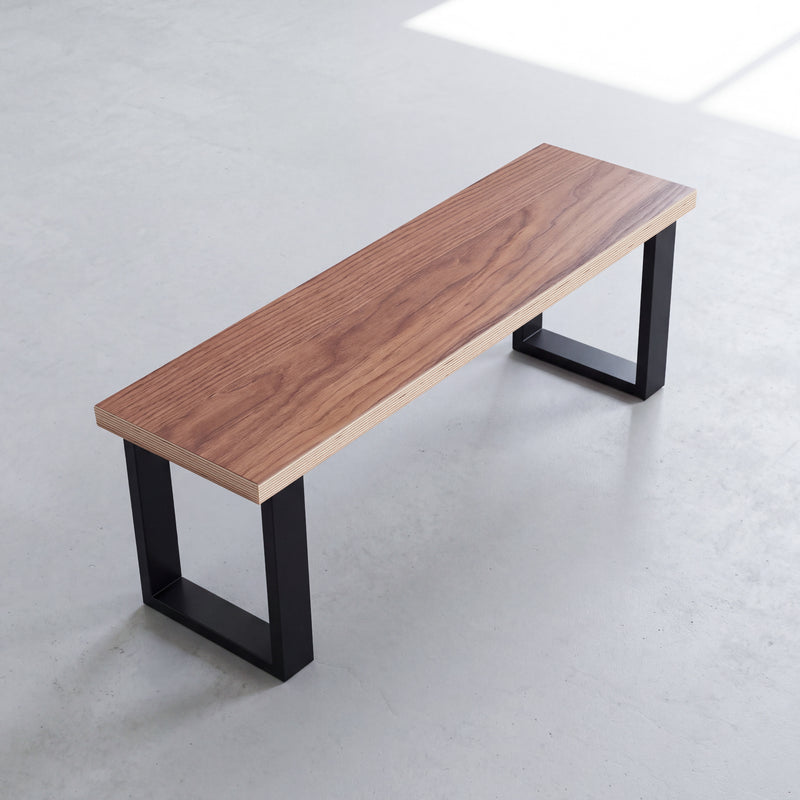 Walnut dining bench with black Square legs, viewed at an angle