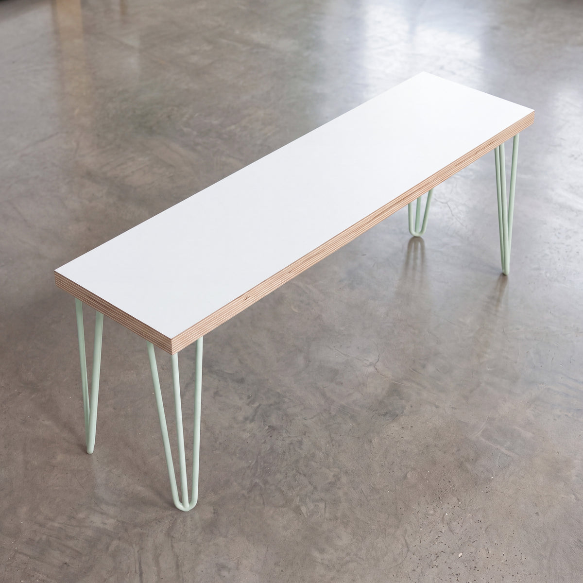 White Formica dining bench with pastel green hairpin legs, viewed at an angle