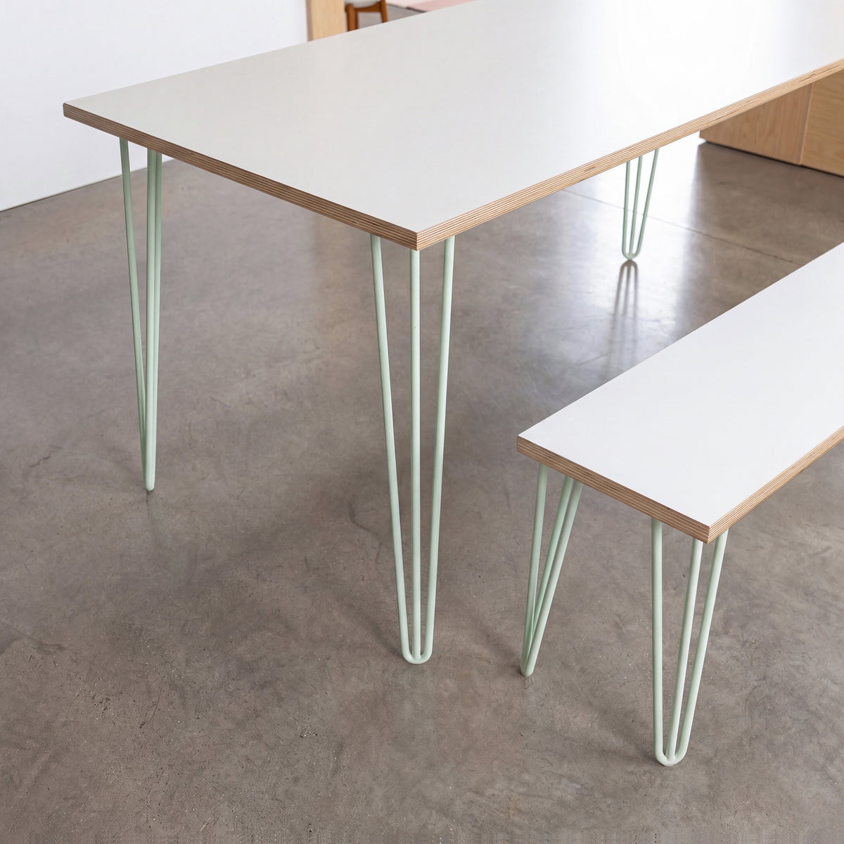 Close-up of a White Formica dining table and matching bench with pastel green hairpin legs