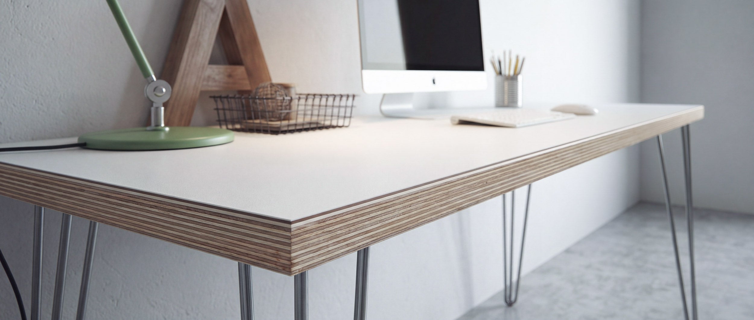 White Formica plywood desk top close-up in a home office, against a white wall and concrete floor