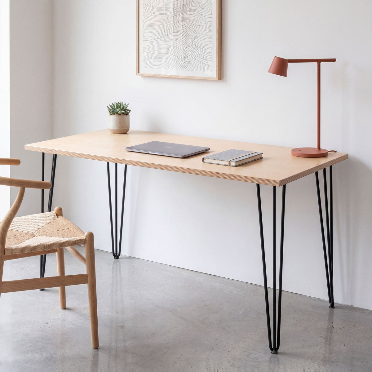 Birch plywood desk with black hairpin legs, styled with a laptop and terracotta lamp