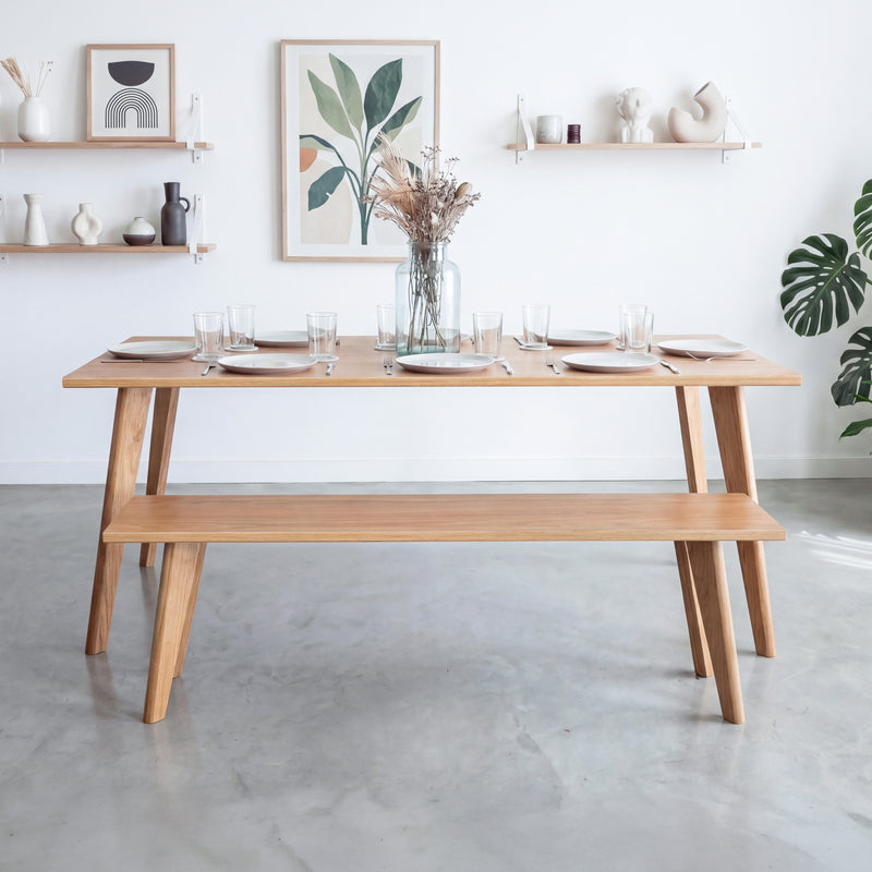 Front view of an oak dining table and matching bench with tapered oak legs